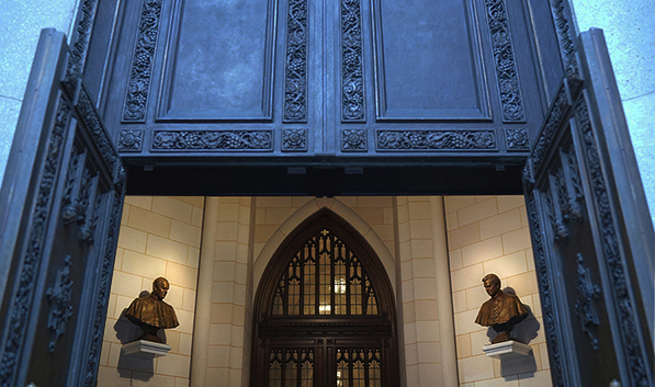 Wide interior view of St. Patrick’s Cathedral entrance showing two bronze busts mounted on either side of a large doorway.