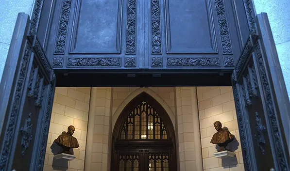 Wide interior view of St. Patrick’s Cathedral entrance showing two bronze busts mounted on either side of a large doorway.