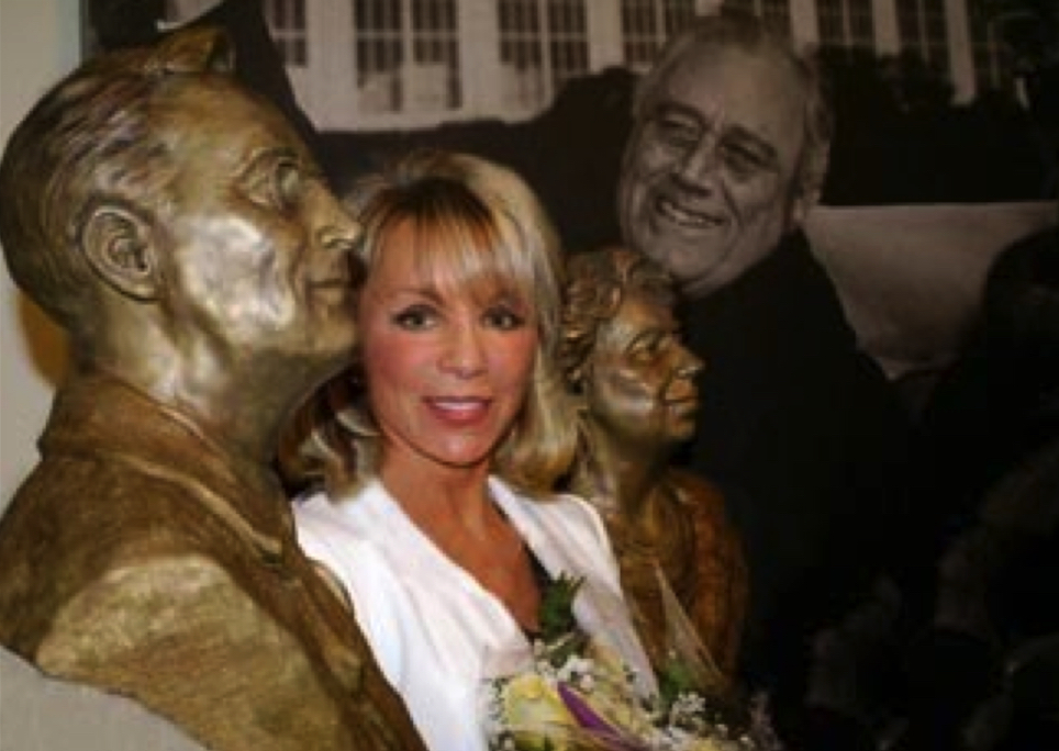 Group standing indoors beside bronze busts during an unveiling event at Hyde Park.