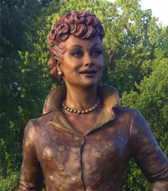 Close-up view of the bronze Lucille Ball statue’s face, framed by greenery.