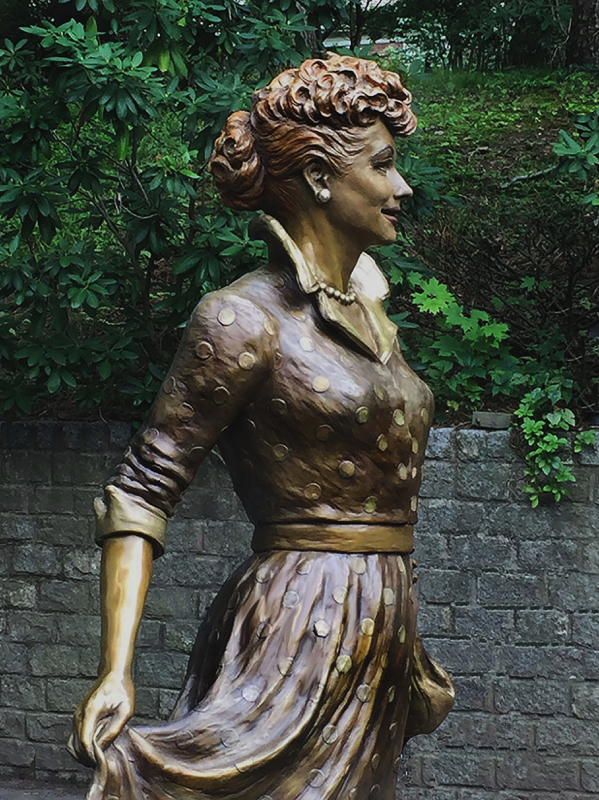 Side view of the bronze Lucille Ball statue, highlighting the pose and movement of the skirt.