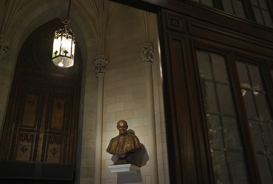 Bronze bust mounted inside St. Patrick’s Cathedral beneath an overhead lantern, shown within the architectural setting.