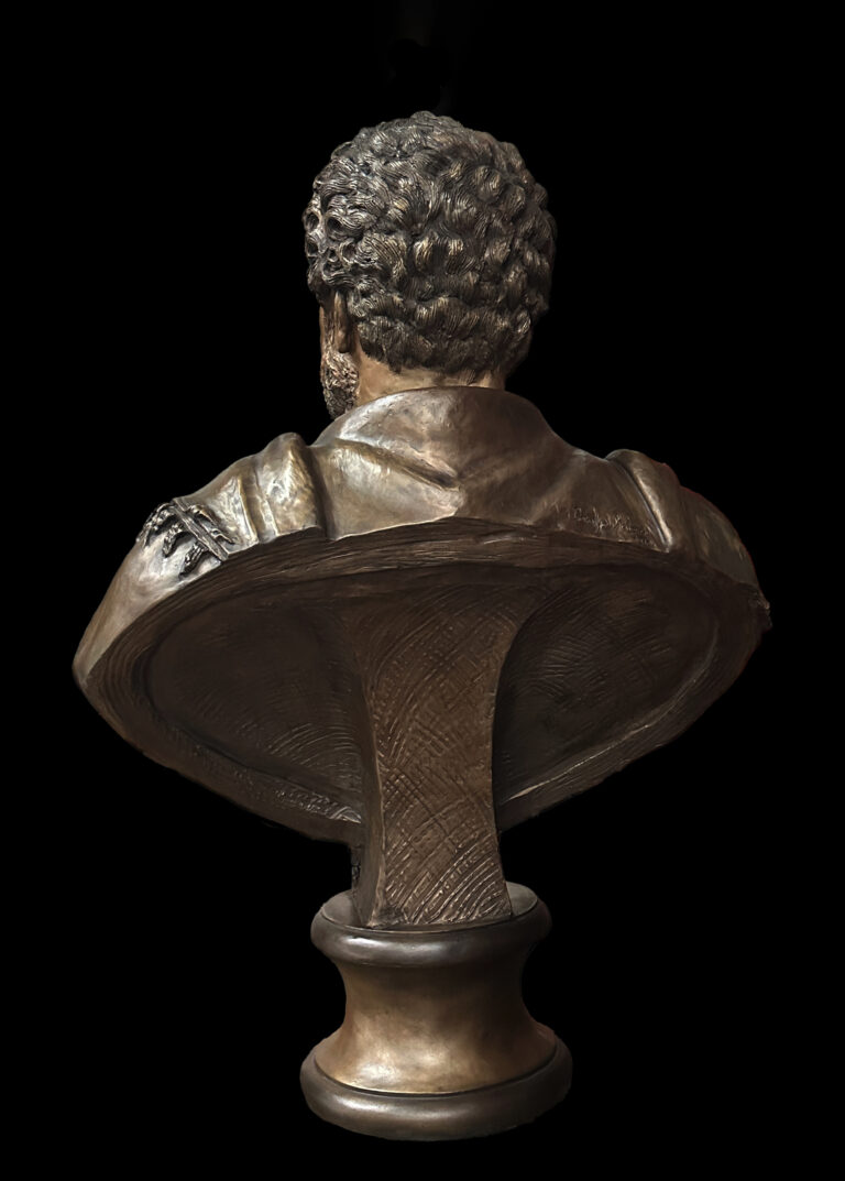 Rear view of the same bronze bust, showing textured hair, draped clothing, and the sculpted base from behind.