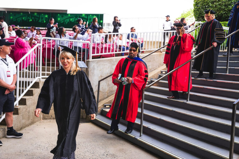 Carolyn D. Palmer walking in academic regalia during a graduation procession, accompanied by faculty members.