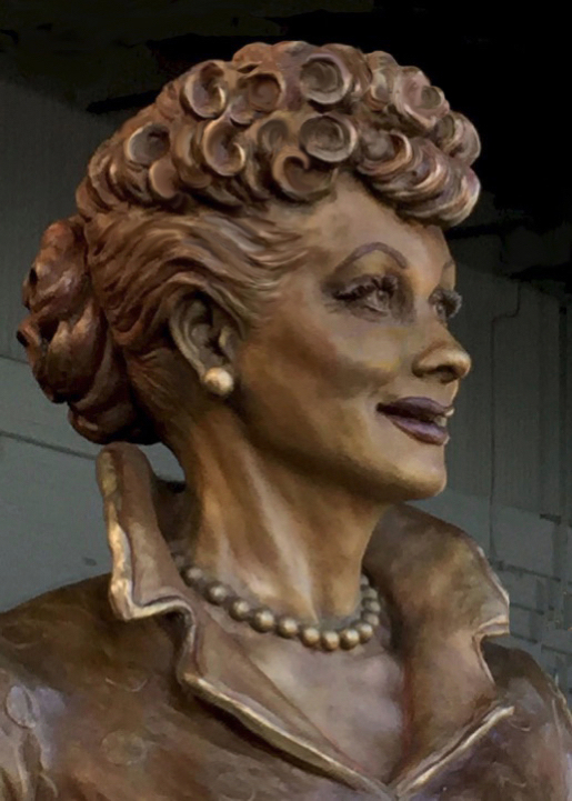 Close-up view of the bronze Lucille Ball sculpture showing her face, hairstyle, and pearl necklace.