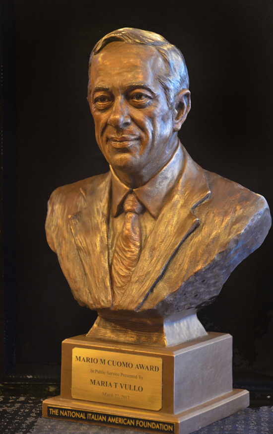 Bronze bust of Mario Cuomo shown from a three-quarter angle, highlighting the sculpted suit and facial detail.