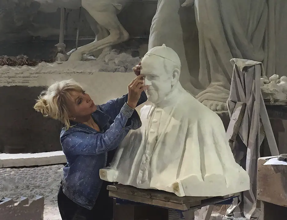 Sculptor Carolyn D. Palmer working on a large sculpture of Pope Francis in a studio.