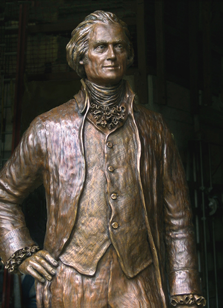 Full-length view of the bronze Thomas Jefferson statue displayed indoors, showing period clothing and formal pose.
