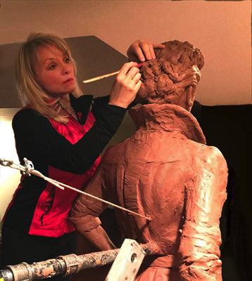 Sculptor Carolyn D. Palmer shaping the clay head of the Lucille Ball sculpture in a studio.
