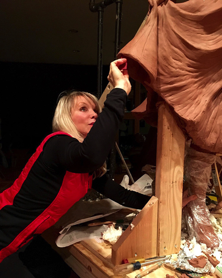 Sculptor Carolyn D. Palmer carving and refining the clay drapery of the Lucille Ball sculpture.