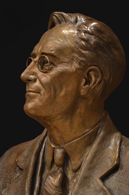 Bronze portrait bust of Franklin D. Roosevelt shown in profile, highlighting facial features and glasses.